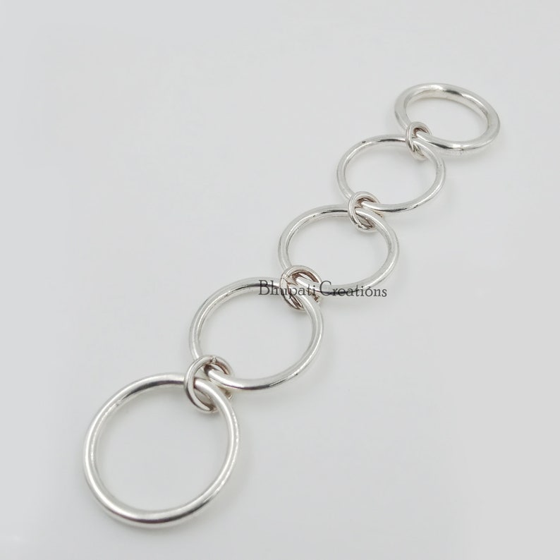 May include: A silver chain made of five interlocking rings.