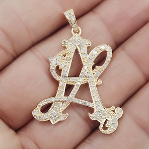 Peut inclure: Un pendentif en or avec une lettre A sertie de diamants. La lettre est dans un style d'écriture cursive.