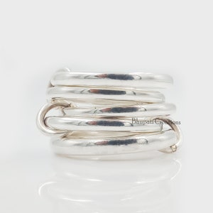 May include: Silver ring with multiple bands twisted together. The ring is made of polished silver and has a smooth, rounded surface.