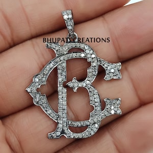 Könnte beinhalten: Ein silberner Anhänger mit einem Diamanten-Monogramm der Buchstaben "BC". Der Anhänger ist im klassischen, verzierten Stil gehalten und perfekt für eine Halskette.