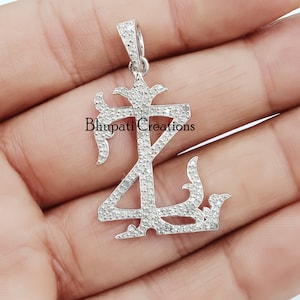 Peut inclure: Un pendentif en argent avec un design stylisé en forme de lettre 'Z', entièrement recouvert de petits diamants transparents. Le pendentif est suspendu à une bélière en argent.