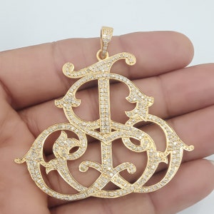 Puede incluir: Un colgante de oro con un diseño de monograma engastado con diamantes. El colgante presenta una 'I' y una 'S' estilizadas entrelazadas.
