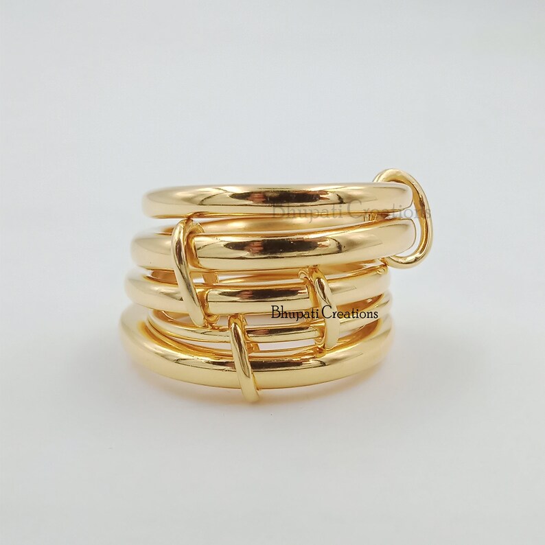 May include: Gold ring made of multiple interlocking bands. The ring is thick and has a shiny finish.