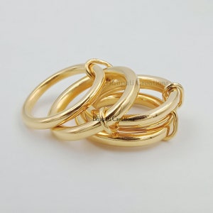 May include: Three gold rings interlocked together. The rings are thick and have a smooth, polished finish.