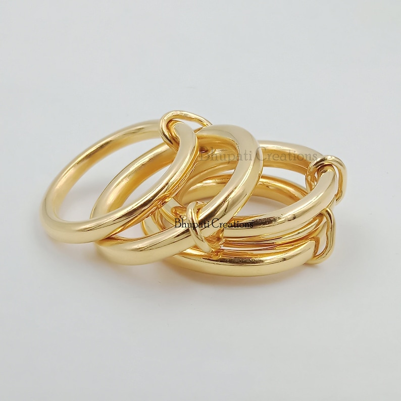May include: Three gold rings interlocked together. The rings are thick and have a smooth, polished finish.