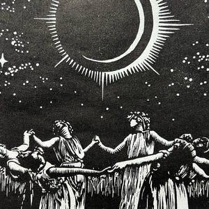 A detail shot of a Black and white art print depicting a celestial scene. A crescent moon with radiating lines is centered above 5 female figures in flowing robes, holding hands in a circle. The background is a starry night sky, with a field of tall grass in the foreground.