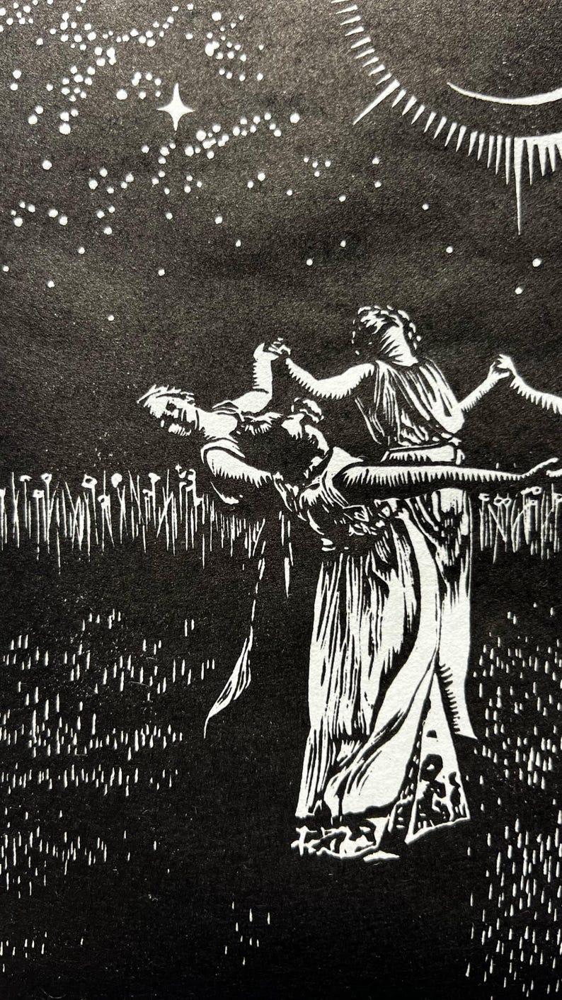 A detail shot of a Black and white art print depicting a celestial scene. A crescent moon with radiating lines is centered above 5 female figures in flowing robes, holding hands in a circle. The background is a starry night sky, with a field of tall grass in the foreground.