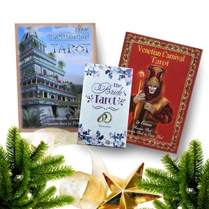 May include: Three different tarot decks: The Babylonian Tarot with a blue and gold cover, The Bride's Tarot with a white and purple cover, and the Venetian Carnival Tarot with a red and gold cover.