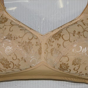 May include: A beige bra with a floral pattern. The bra has adjustable straps and a hook and eye closure in the back.