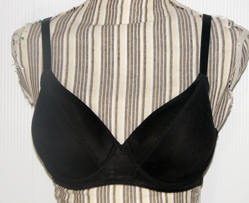May include: A black bra with adjustable straps. The bra has a smooth, seamless cup and a lace trim.