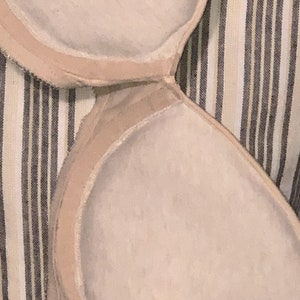 May include: Close-up of the inside of a nude-colored bra cup. The cup is made of a soft, smooth fabric and has a seamless design.