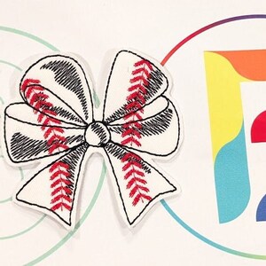Puede incluir: Moño de tela blanco con costuras rojas en forma de pelota de béisbol. El moño está sobre un fondo blanco con una letra "B" de colores arcoíris en un círculo.