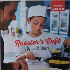 May include: A book cover featuring a young boy wearing a white chef's hat, cooking scrambled eggs. The book title is "Rooster's Cafe" by Jack Deen. The book cover also includes the text "Foreword by Jamie Deen" and "Favorite recipes any kid can cook".