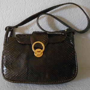 May include: A brown snakeskin shoulder bag with a gold-toned clasp. The bag has a flap closure and a long strap.