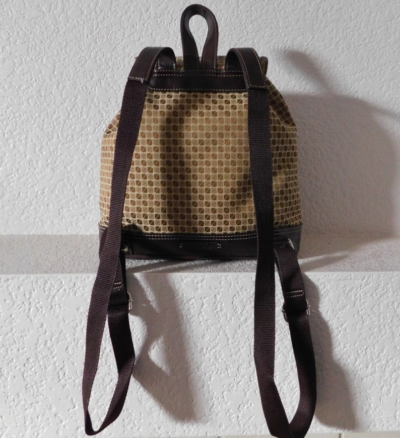 May include: A brown and beige patterned backpack with adjustable straps. The backpack has a drawstring closure and a brown leather trim.