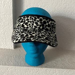 May include: A black and white leopard print visor with a black band around the edge.