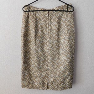 May include: A brown and cream patterned skirt with a back zipper closure. The skirt is hanging on a black hanger.