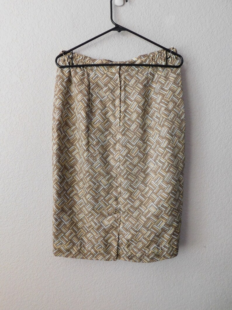 May include: A brown and cream patterned skirt with a back zipper closure. The skirt is hanging on a black hanger.