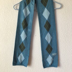 May include: A blue and brown argyle patterned scarf with a small tag that says "Washable" on it.