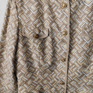 May include: A brown and white patterned blazer with gold buttons and a decorative trim. The label reads "Adrienne Vittadini PAPEL".