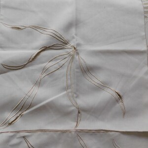 Pu&ograve; includere: Tovaglioli di lino bianco sporco con ricami floreali. Ogni tovagliolo presenta un motivo floreale centrale stilizzato in filo marrone chiaro. Il ricamo crea un motivo delicato e strutturato sul tessuto. I tovaglioli sono quadrati.