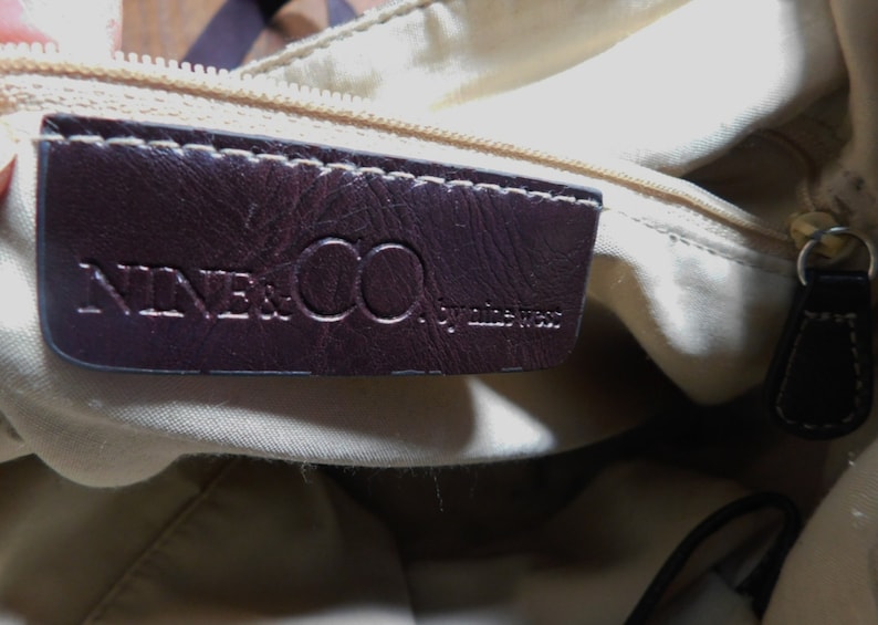 May include: A brown leather tag with the text "NINE & CO. by nine west" inside a beige fabric handbag.