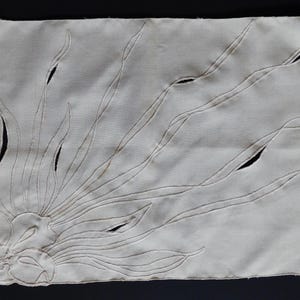 Pu&ograve; includere: Tovaglietta rettangolare color crema con un ricamo floreale. Il disegno presenta un fiore stilizzato e lunghe linee curve che si irradiano verso l'esterno, con dettagli ritagliati. La tovaglietta &egrave; realizzata in tessuto morbido e strutturato.