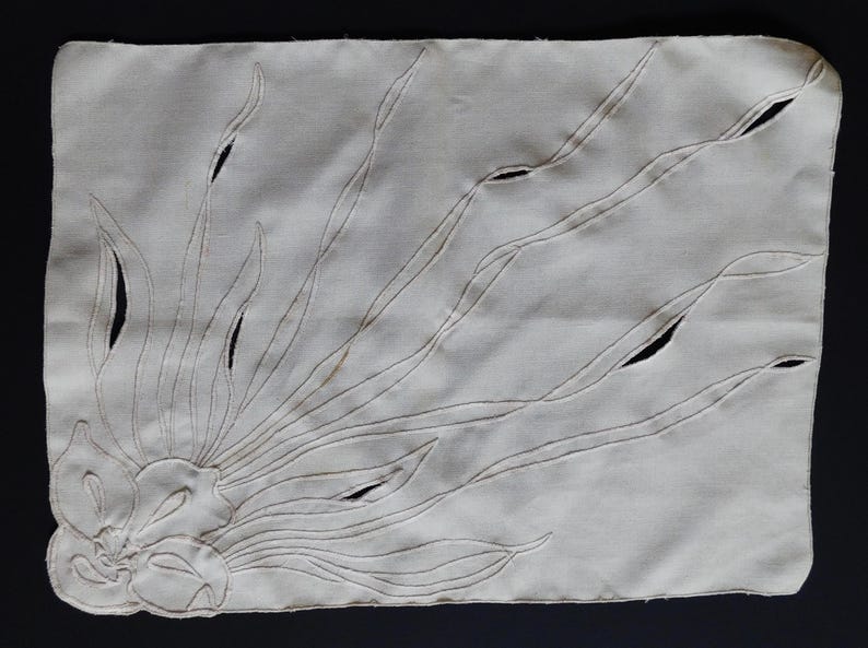 Pu&ograve; includere: Tovaglietta rettangolare color crema con un ricamo floreale. Il disegno presenta un fiore stilizzato e lunghe linee curve che si irradiano verso l'esterno, con dettagli ritagliati. La tovaglietta &egrave; realizzata in tessuto morbido e strutturato.