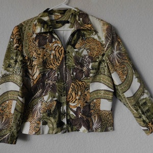May include: A green, brown, and white jacket with a zipper closure and a leopard and tiger print. The jacket has a sequined design.
