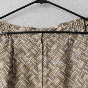May include: Brown and beige patterned shorts with an elastic waistband. The shorts are hanging on a black hanger.