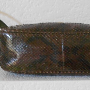 May include: A brown snakeskin handbag with a short strap. The bag has a textured, diamond-shaped pattern.