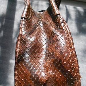 May include: A brown snakeskin handbag with a unique, textured pattern. The bag has a single strap and a top flap closure.