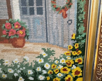 framed needlepoint wall art cottage house with white chair and flowers