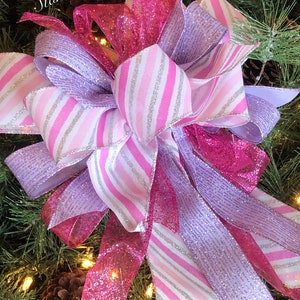 K&ouml;nnte beinhalten: Ein rosa-lila Weihnachtsbaumspitzen-Schleife mit silber-wei&szlig; gestreiftem Band. Die Schleife besteht aus glitzerndem Netzband.