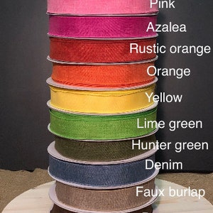 May include: A stack of 11 different colored ribbon spools, each with a label indicating its color. The colors are red, pink, azalea, rustic orange, orange, yellow, lime green, hunter green, denim, faux burlap, and brown. The bottom spool is brown and the top spool is red. The label at the bottom of the stack reads "Starr Events".