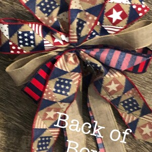 May include: A red, white, and blue patriotic bow with a burlap ribbon and a star pattern. The bow is tied with a burlap ribbon and has a "Back of Bow" label.