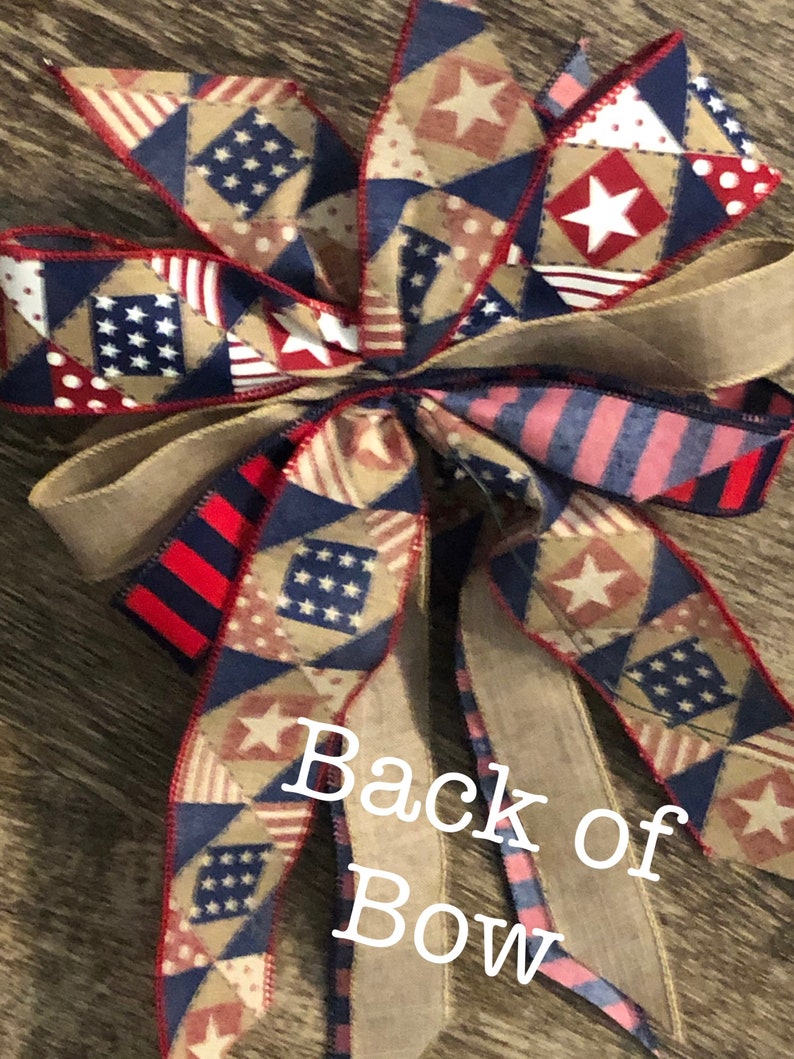 May include: A red, white, and blue patriotic bow with a burlap ribbon and a star pattern. The bow is tied with a burlap ribbon and has a "Back of Bow" label.