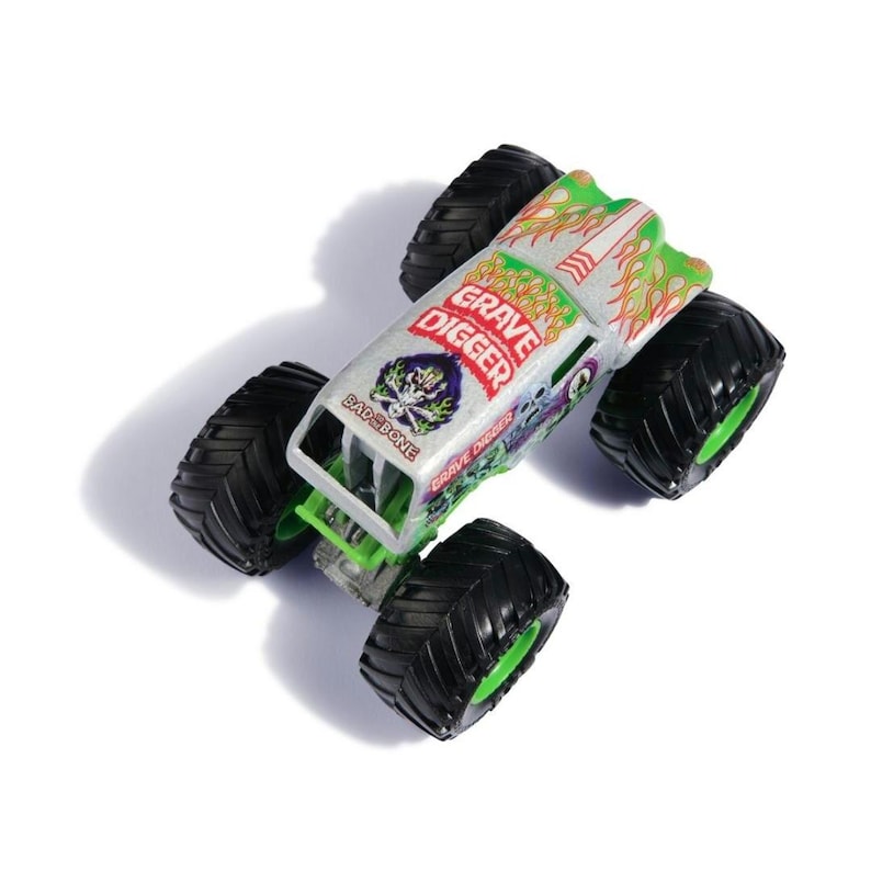 May include: A toy monster truck with the words "Grave Digger" in red and green. The truck has a silver body with green and orange flame designs and large black tires with green rims. The text "Bad Bone" is also visible.
