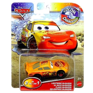 May include: A Lightning McQueen toy car from the Disney Pixar Cars series. The toy is in a plastic package with the words "Color Changers" and "2 in 1" printed on it. The car is yellow and orange with the number 95 on it. The package also includes the text "Lightning McQueen, El Rayo McQueen, Flash McQueen, Relampago McQueen".