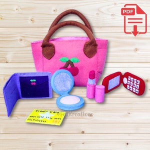 May include: Felt play set for pretend play, featuring a pink handbag with a cherry design, a purple wallet, a blue compact mirror, a pink lipstick, a red cell phone, and a yellow credit card that says "My Princess".
