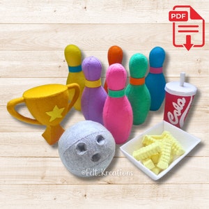 Könnte beinhalten: Ein Filz-Bowling-Set mit einer goldenen Trophäe, einer grauen Bowlingkugel und bunten Pins. Enthält einen Soda-Becher, einen Teller Pommes und den Text "Felt Kreations". Ein PDF-Download-Symbol befindet sich oben rechts.