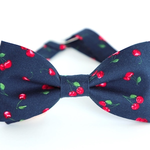 May include: A navy blue bow tie with a cherry print.
