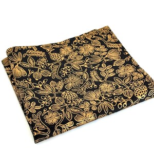 Puede incluir: Un pa&ntilde;uelo de bolsillo negro con un patr&oacute;n floral dorado. El patr&oacute;n presenta hojas, flores y bayas.