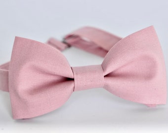 May include: A dusty rose bow tie made of fabric. The bow tie is tied and ready to wear.