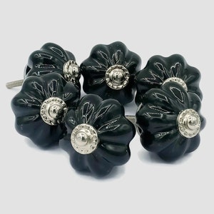 Puede incluir: Seis pomos de armario de cerámica negra con un diseño acanalado y detalles plateados.