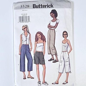 Op de afbeelding: Een vintage Butterick naaipatroon, nummer 3528, met illustraties van dameskledingontwerpen. De ontwerpen omvatten broeken, shorts en tops. Het patroon is gedrukt op wit papier met zwarte tekst en illustraties.