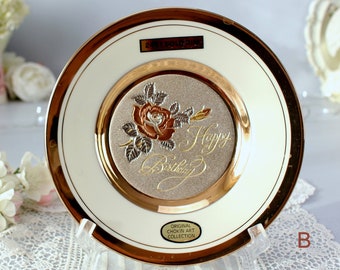 May include: A decorative plate with a gold rim and a central design featuring a rose and the words "Happy Birthday" in gold script. The plate has a cream-colored background and is part of the "Original Chokin Art Collection".