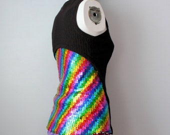 May include: A sleeveless top with a black textured fabric on the upper portion and a vibrant, sequined rainbow design on the lower section. The sequins create a diagonal striped pattern with a spectrum of colors.