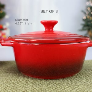 Op de afbeelding: Set van drie rode keramische ramekins met deksels. Elk ramekin heeft een diameter van 11 cm.