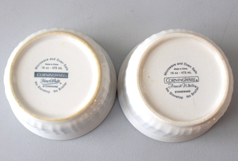 May include: Two white stoneware bowls with textured sides. The bowls are marked "French White" and "16 oz - 473 ml". The bowls are microwave and oven safe. The bowls are made in China.